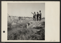 [recto] Young volunteer Nisei agricultural foreman inspects site for the drainage ditch bridge, together with an agricultural division foreman and superintendent. ;  Photographer: Parker, Tom ;  Topaz, Utah.