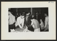 [recto] Newcomers from Tule Lake are receiving their assignments in Warehouse 12 before being transported to their blocks. ;  Photographer: Lynn, Charles R. ;  Dermott, Arkansas.