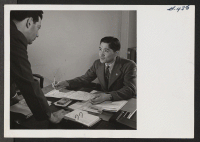 [recto] Ray Hashitani did not live in a relocation center but came to Washington a year ago from his home in Oregon. However, many of his friends are at Minidoka. He is now working for the O.P.A. and is shown here consulting with another member of the agency.
