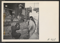 [recto] The treads on a caterpillar tractor are repaired by local mechanics. All repair work on cars, trucks, tractors, and other motor vehicles is done by evacuee workers. ;  Photographer: Stewart, Francis ;  Newell, California.