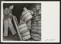 [recto] Gathering a supply of food stuffs, in the produce cooler for delivery to center mess halls, are these two young former Californians (former west coast persons of Japanese ancestry). ;  Photographer: Parker, Tom ;  McGehee, Arkansas.