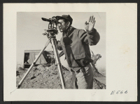 [recto] A young Nisei operates a surveying instrument in laying out the grounds for administrative quarters. ;  Photographer: Parker, Tom ;  Amache, Colorado.