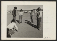 [recto] It is a cold December day, but what does the weather have to do with a serious game of lag marbles. ;  Photographer: Parker, Tom ;  Amache, Colorado.